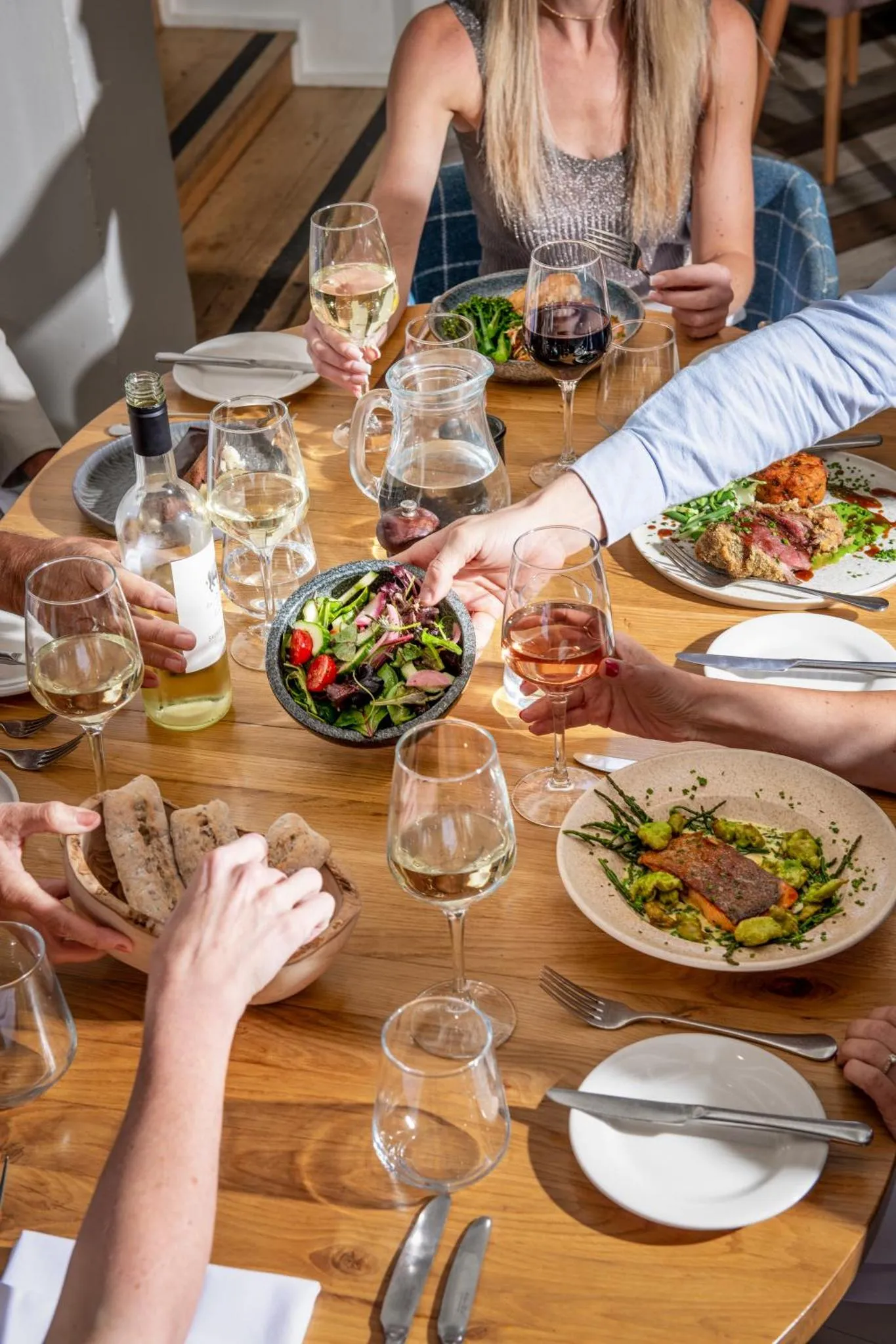 Une table est dressée avec des plats et des boissons, entourée de convives.