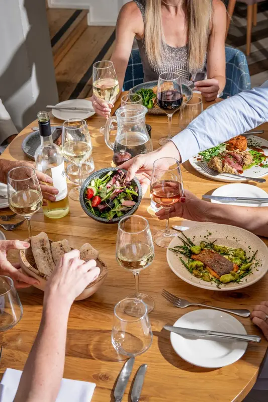 Une table est dressée avec des plats et des boissons, entourée de convives.