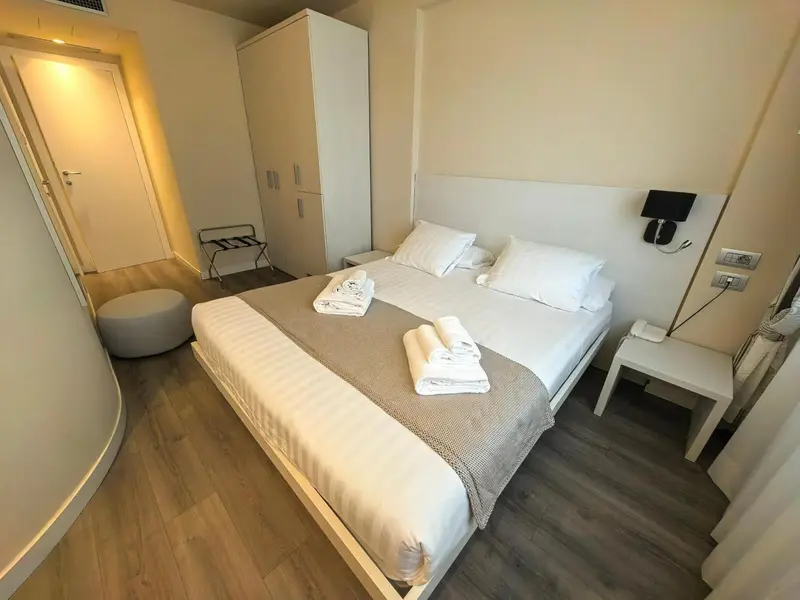 Une chambre lumineuse avec un grand lit recouvert d'une couette blanche et de coussins.
