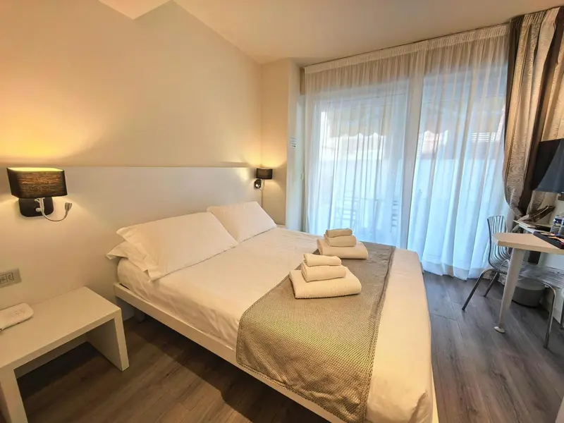 Une chambre lumineuse avec un grand lit et des rideaux blancs.