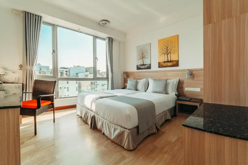 Chambre lumineuse avec un grand lit et une vue sur la ville.
