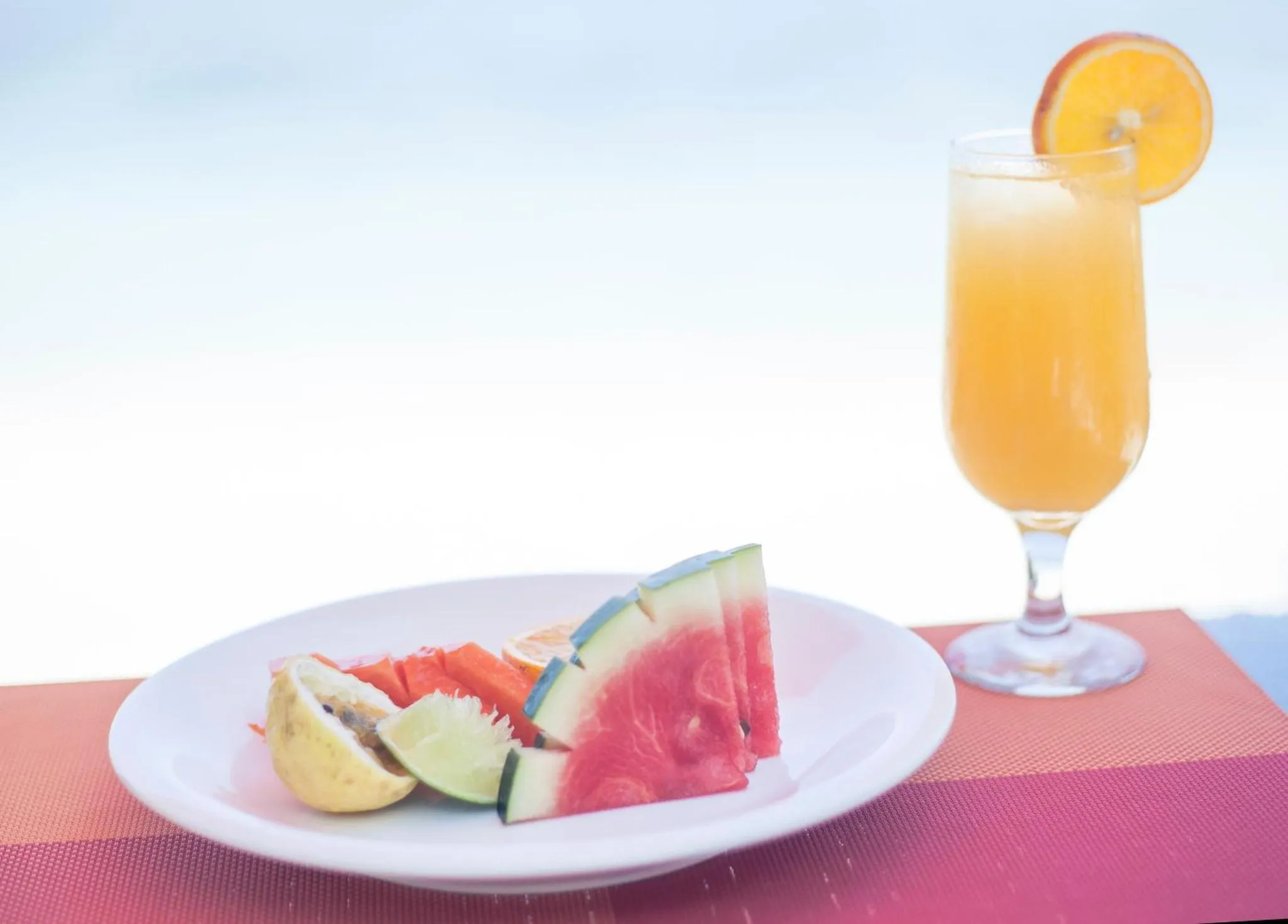 Assiette de fruits frais et verre de jus d'orange sur une table.