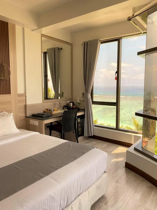 Une chambre lumineuse avec un lit et un bureau donnant sur la mer.