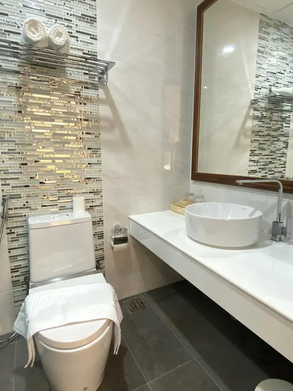 Une salle de bain moderne avec des carreaux décoratifs et des sanitaires blancs.