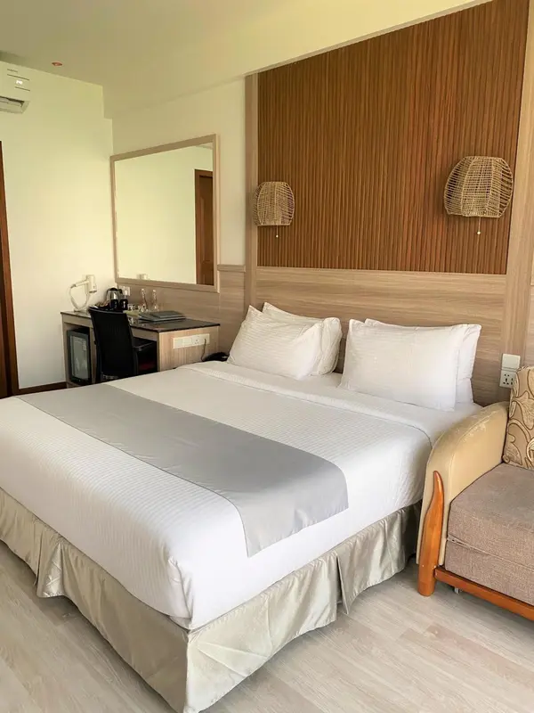 Une chambre d'hotel avec un grand lit recouvert d'une courtepointe blanche.