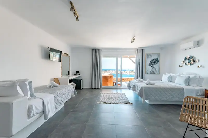 Une chambre lumineuse avec deux lits et une vue sur la mer.