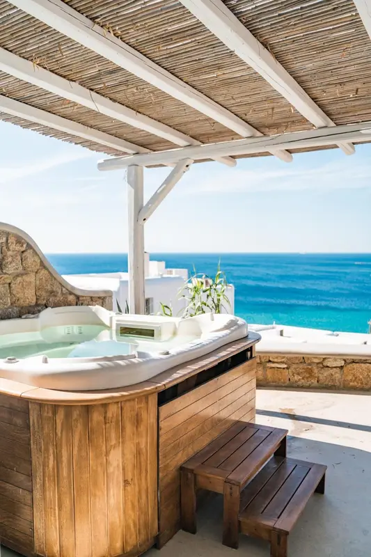 Un jacuzzi en bois sur une terrasse avec vue sur la mer.