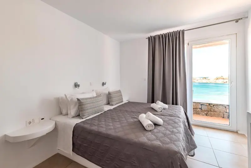 Une chambre lumineuse avec un lit double et une vue sur la mer.
