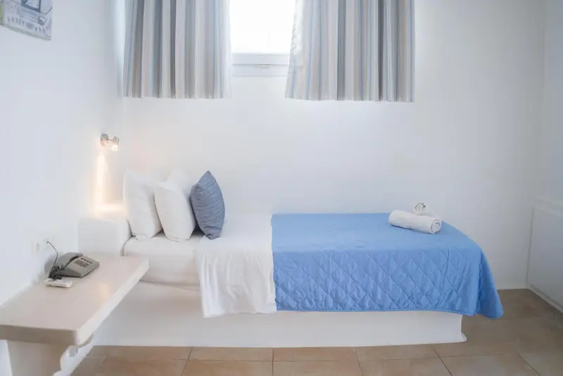 Une chambre lumineuse avec un lit simple et une table de chevet.