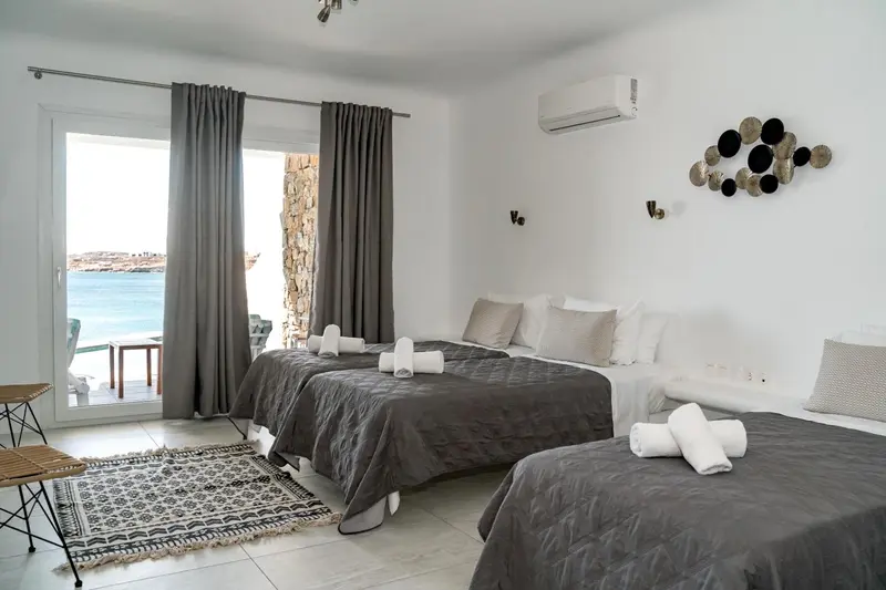 Chambre lumineuse avec lits jumeaux et vue sur la mer.