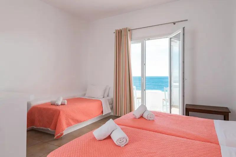 Chambre lumineuse avec deux lits simples et une vue sur la mer.