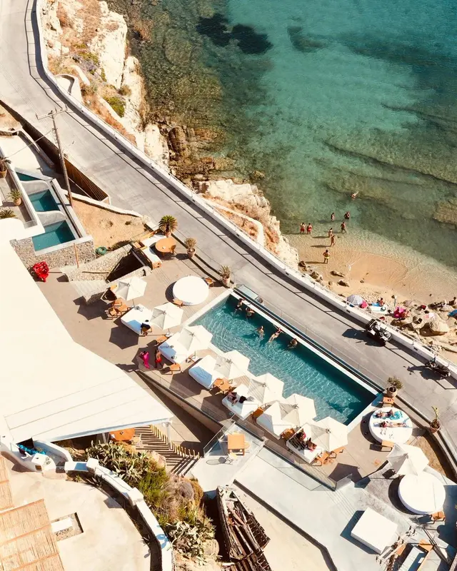 Vue aérienne d'une piscine avec des transats et des parasols près d'une plage.