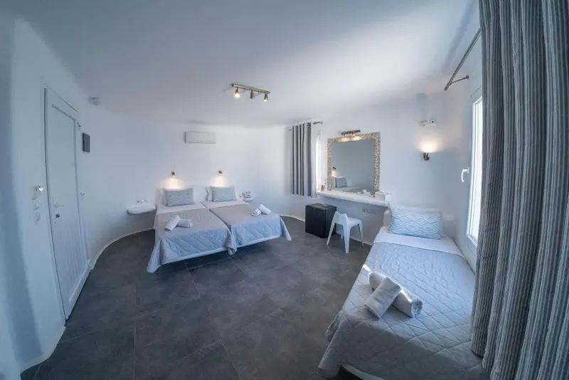 Chambre lumineuse avec deux lits simples et un lit individuel.