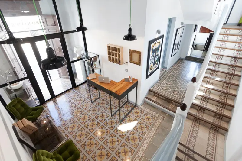 Vue d'intérieur d'un hall d'accueil avec un comptoir et un escalier décoré de motifs.