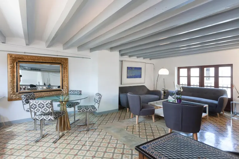 Un salon lumineux avec un coin repas et un grand miroir doré.