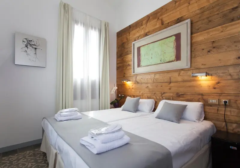 Une chambre lumineuse avec un lit recouvert de linge blanc et un mur en bois.