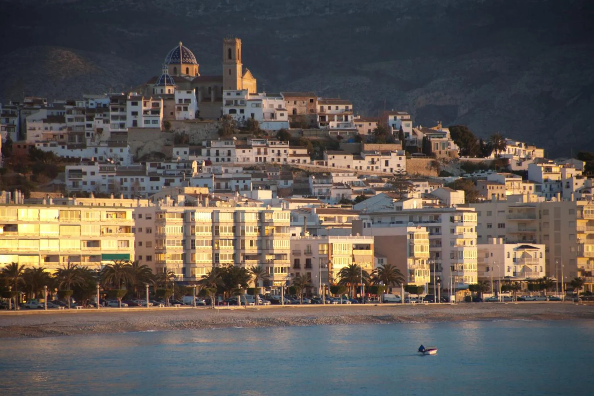 Vue d'une ville blanche sur une colline surplombant la mer.