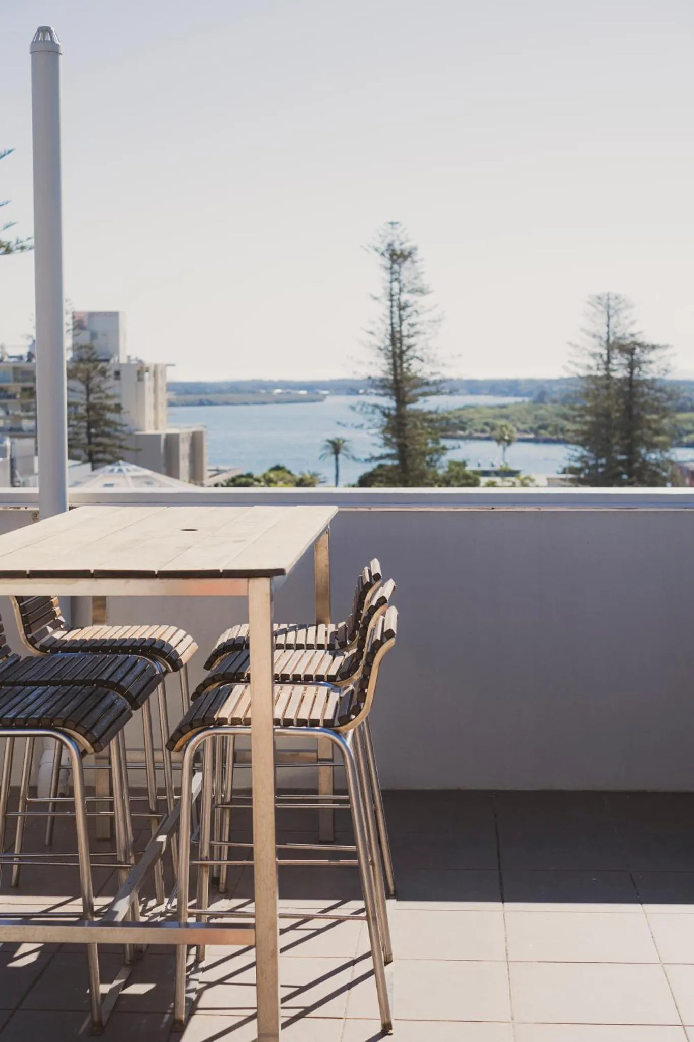 Tables et chaises sur une terrasse avec vue sur la mer et la végétation.