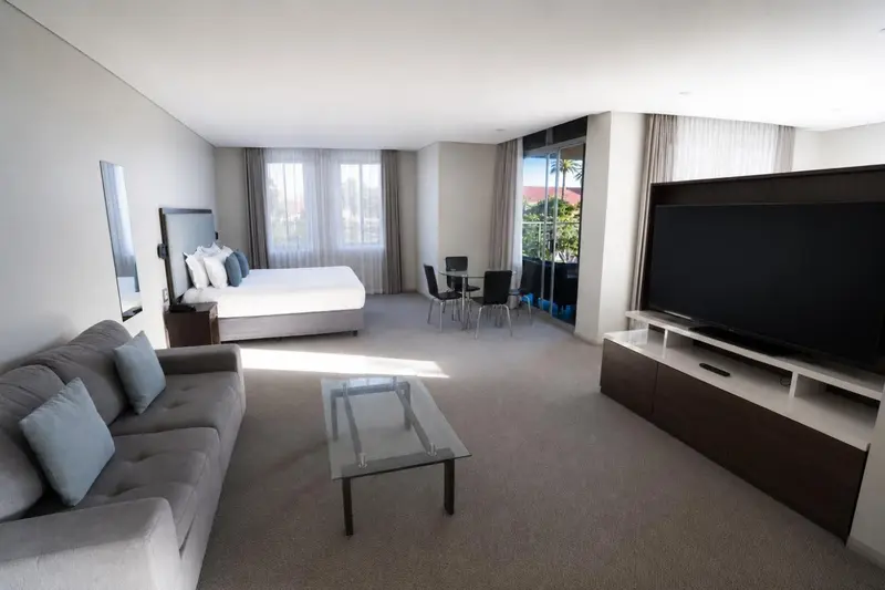 Espace de vie lumineux avec canapé, table basse et télévision à écran plat.