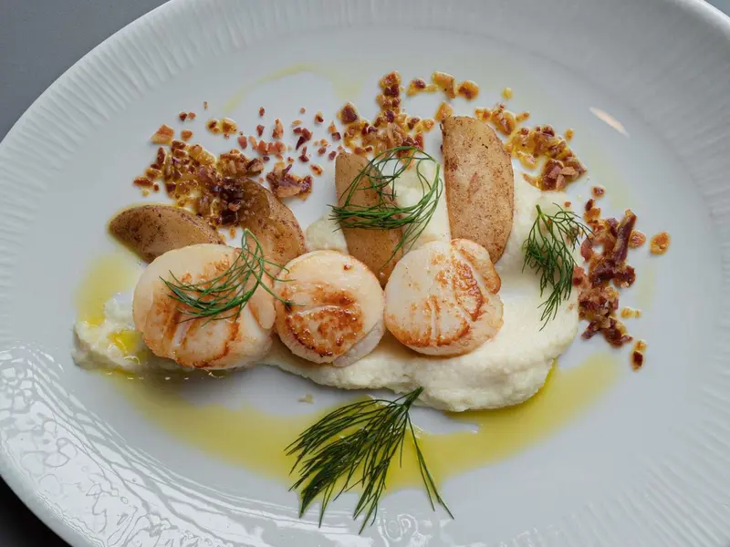 Assiette de noix de Saint-Jacques à la crème et aux herbes.