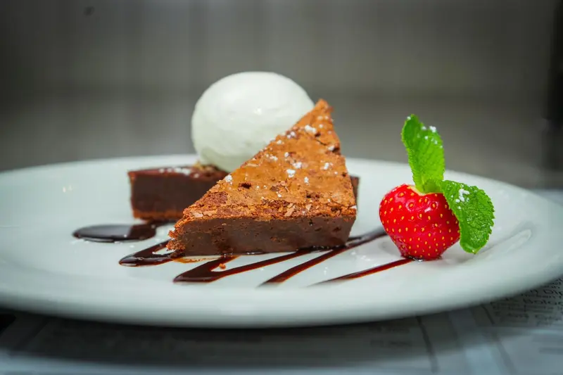 Une part de brownie au chocolat est servie avec une boule de glace et une fraise.