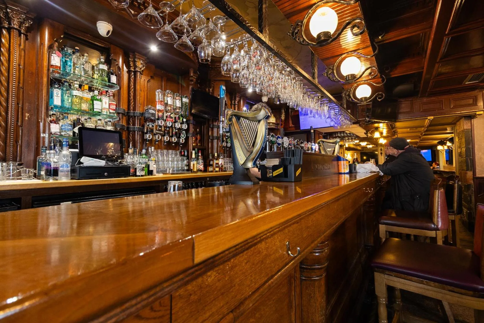 Un comptoir de bar en bois sombre présente une variété de bouteilles et de verres.