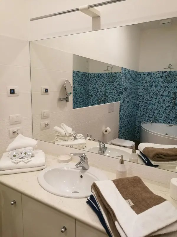 Une salle de bain claire avec lavabo, miroir et douche.