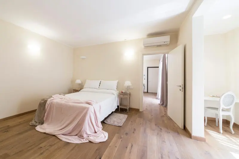 Une chambre lumineuse avec un lit double et un coin bureau.