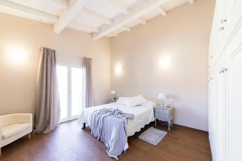 Une chambre lumineuse avec un lit blanc et des rideaux gris.
