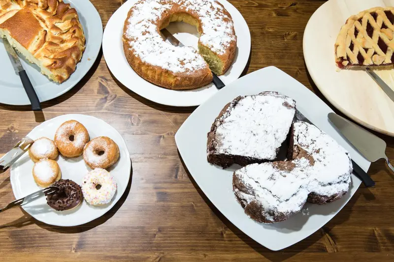 Assortiment de pâtisseries saupoudrées de sucre sur un fond en bois.