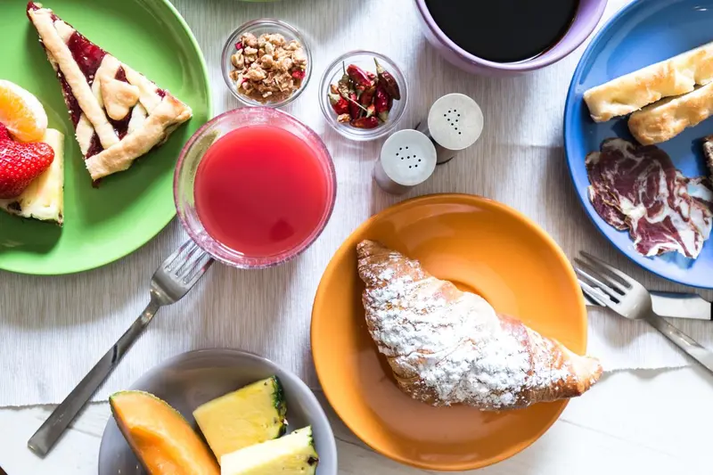 Assortiment de viennoiseries, fruits et boissons sur une table.