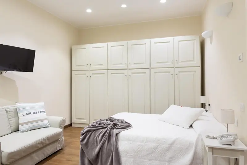 Une chambre lumineuse avec un grand lit et des rangements.