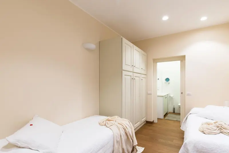 Une chambre lumineuse avec deux lits simples et une armoire.