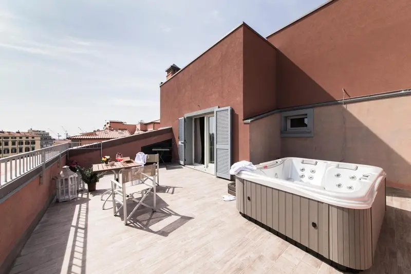 Terrasse aménagée avec jacuzzi et mobilier de jardin offrant une vue sur la ville.