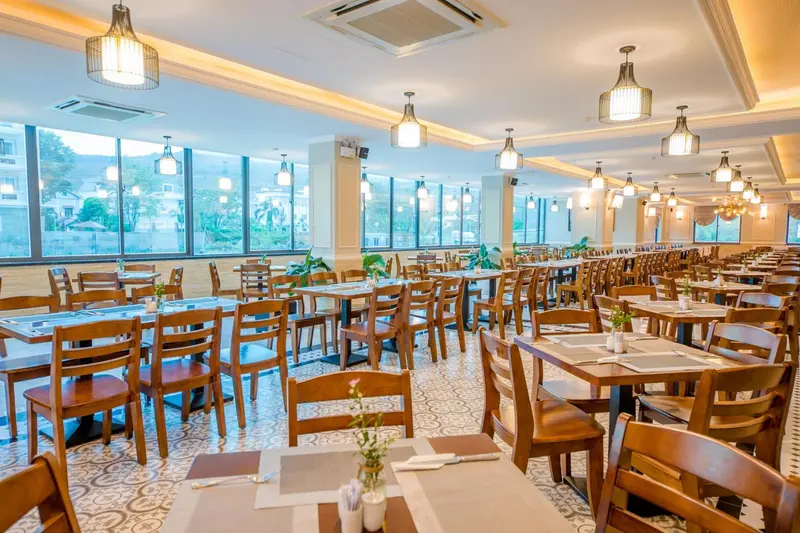 Une salle lumineuse avec des tables dressées pour un repas.