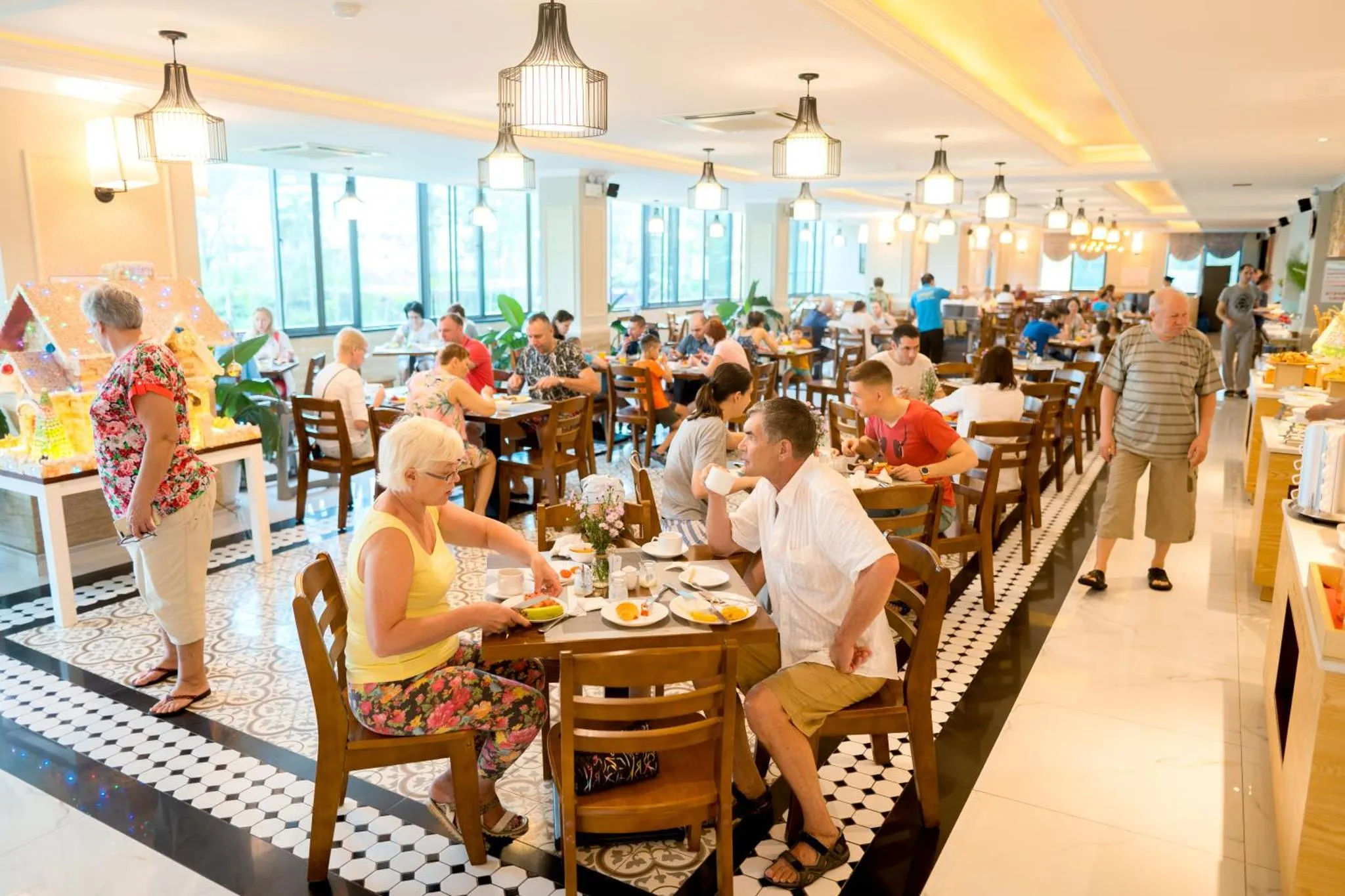 Une salle lumineuse accueille des convives autour de tables dressées pour un repas.