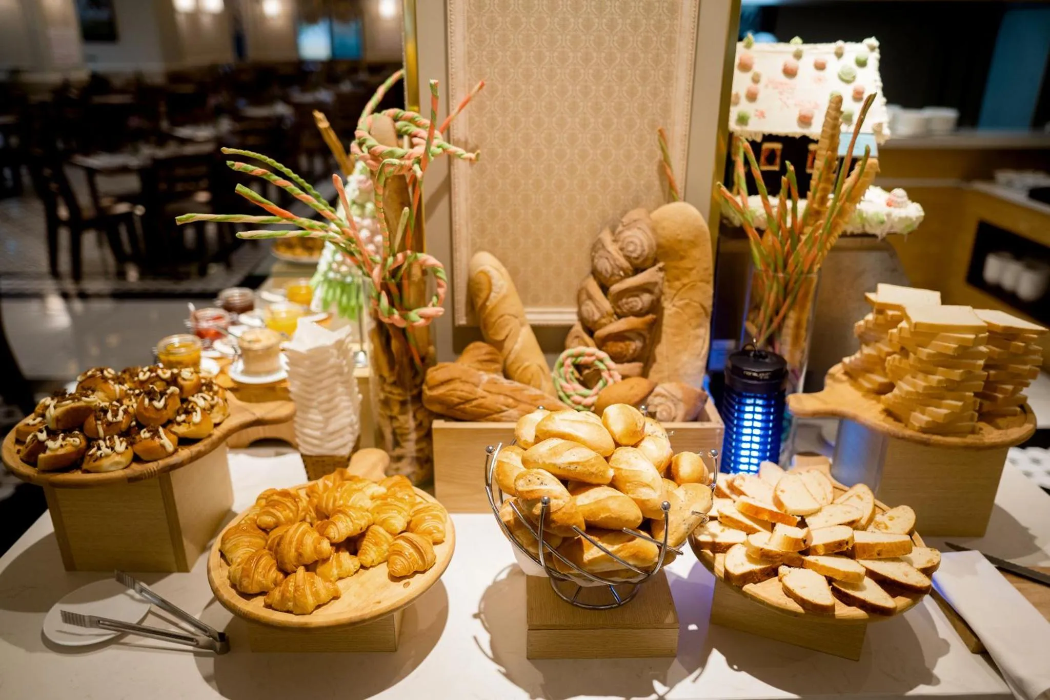 Présentation de viennoiseries et de pains variés sur un buffet.