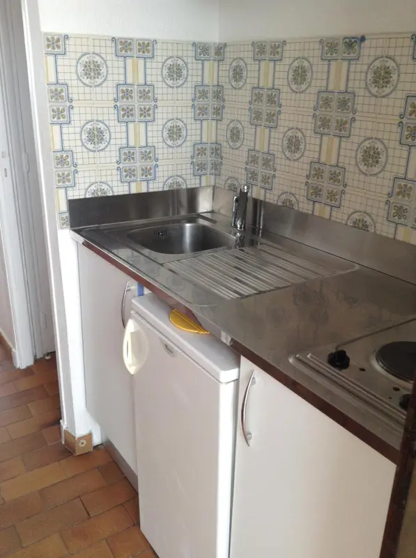 Une kitchenette lumineuse avec un plan de travail en inox et des carreaux décoratifs.