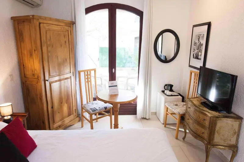 Une chambre lumineuse avec un lit, une table ronde et un placard en bois.