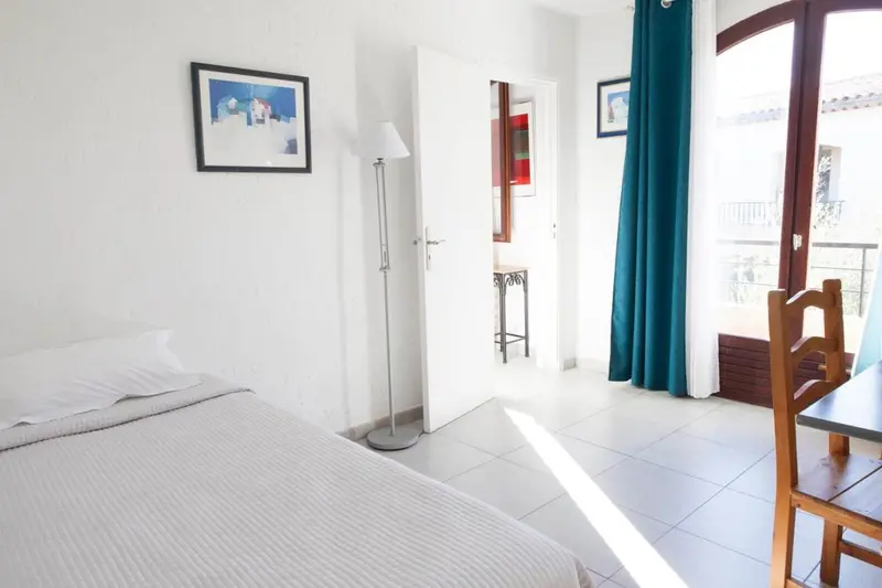 Une chambre lumineuse avec un lit simple et un accès à une terrasse.