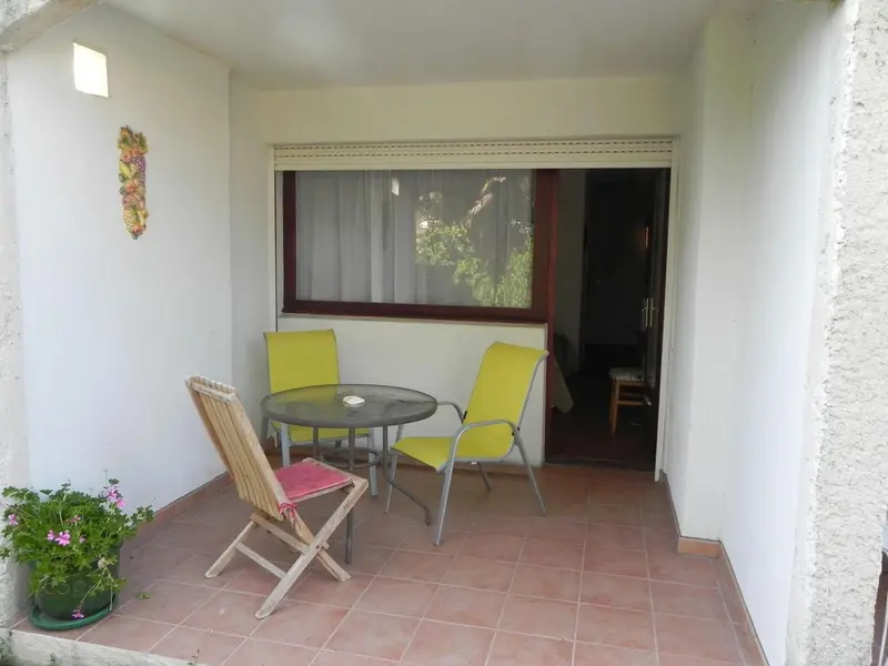 Une terrasse avec une table et des chaises en plastique jaune.