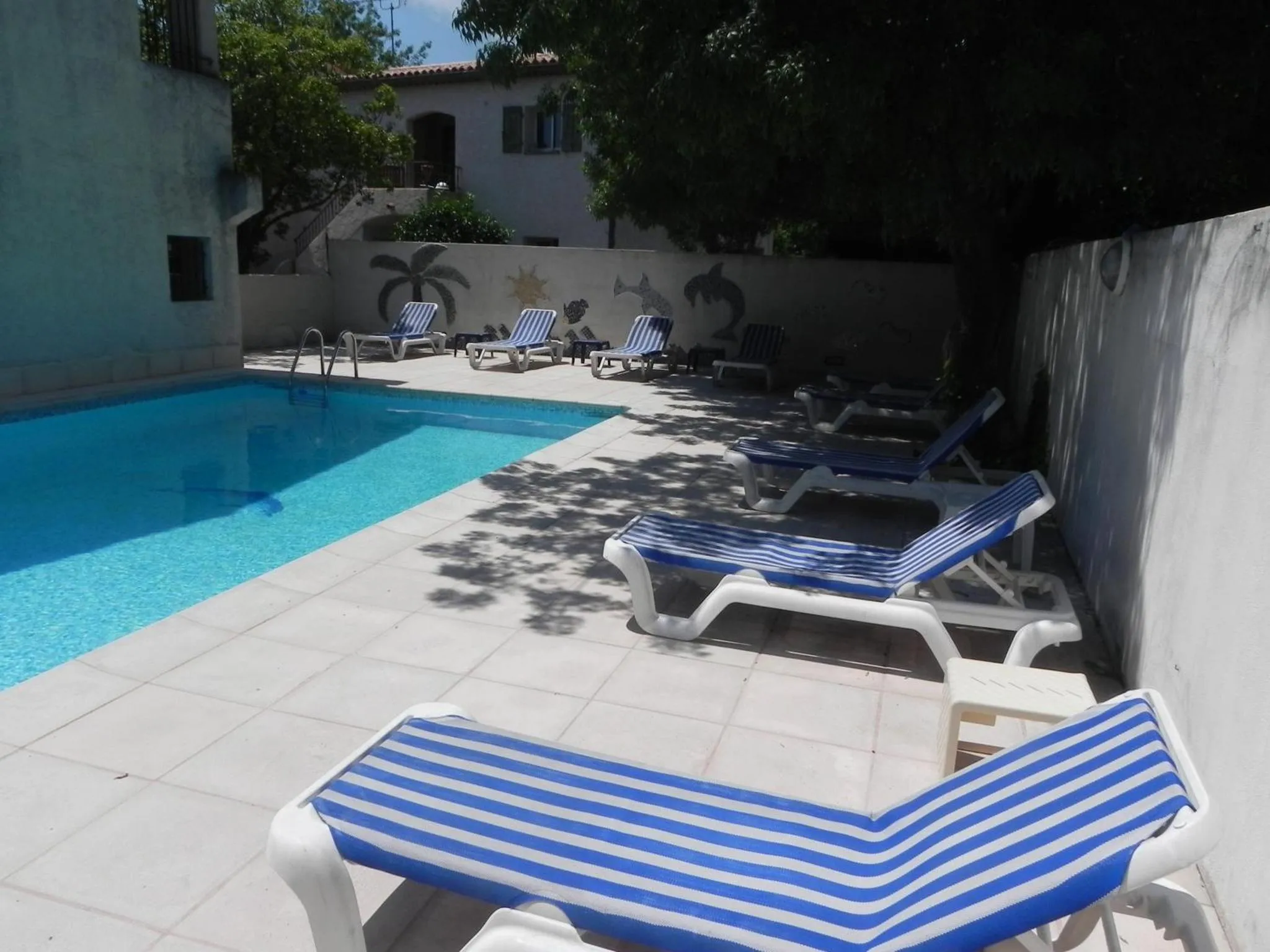 Transats bleus et blancs disposés autour d'une piscine ensoleillée.