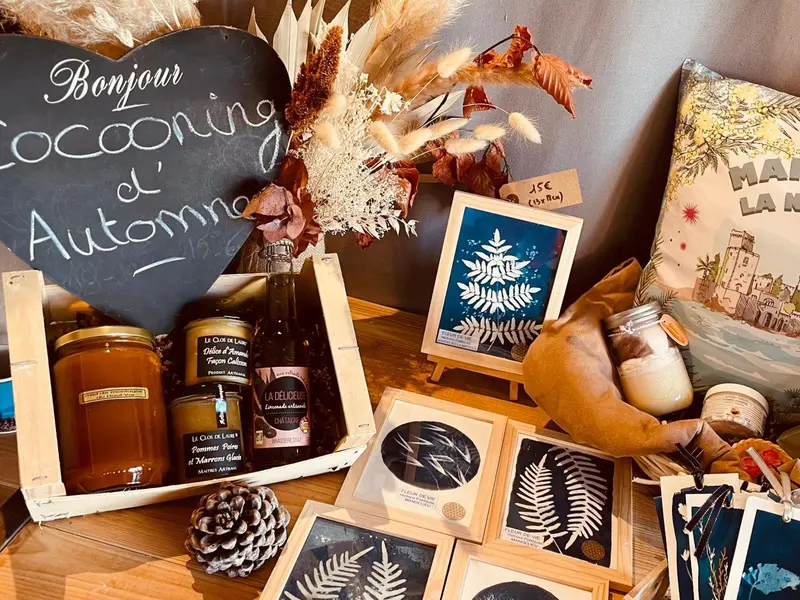 Une table en bois présente des pots de confiture, des cadres et des décorations florales.