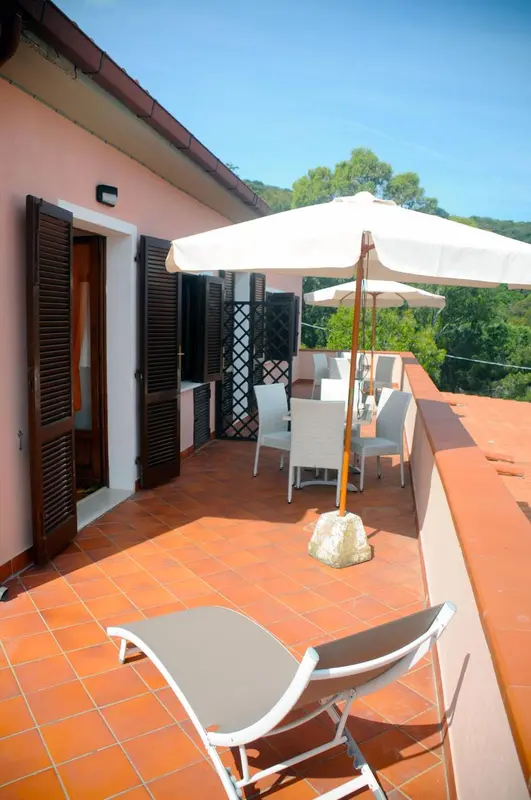 Terrasse carrelée avec mobilier d'extérieur et vue sur la végétation.