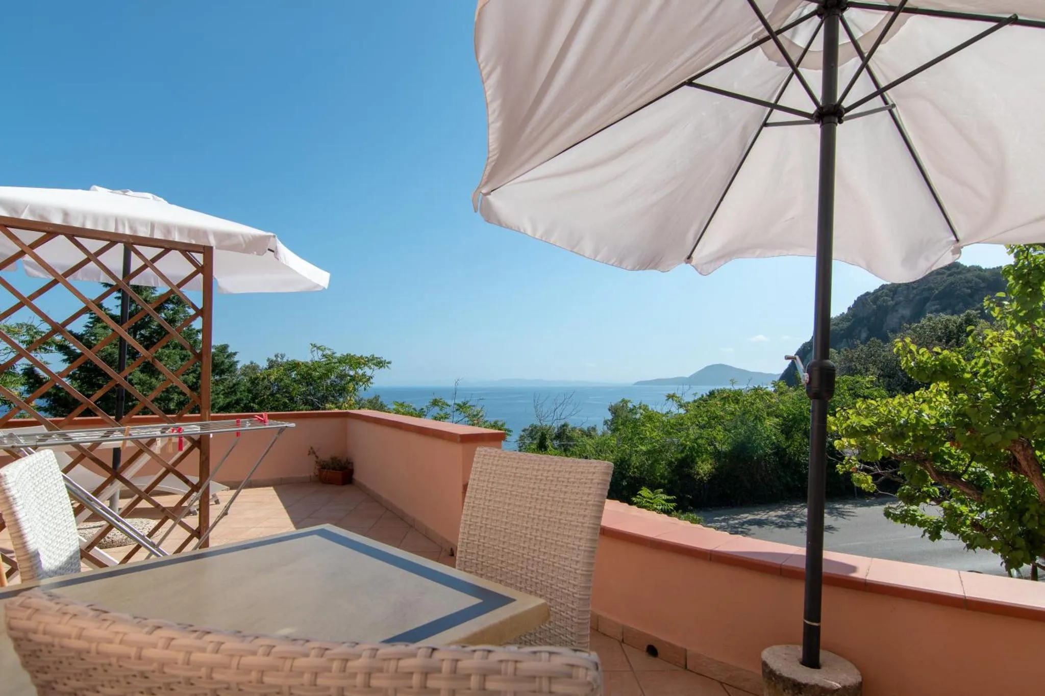 Terrasse ombragée avec vue sur la mer et la végétation.