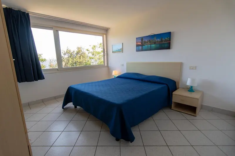 Une chambre lumineuse avec un grand lit et une fenêtre donnant sur l'extérieur.