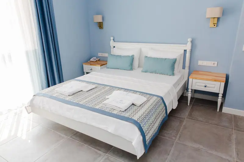 Une chambre lumineuse avec un grand lit recouvert d'une courtepointe et de coussins.