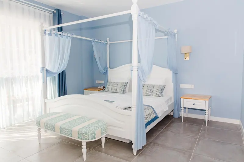 Une chambre lumineuse avec un lit à baldaquin blanc et des rideaux vaporeux.