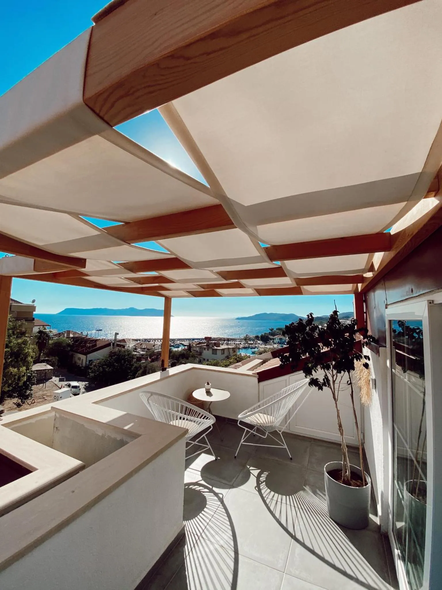 Terrasse ombragée avec mobilier d'extérieur et vue sur la mer.