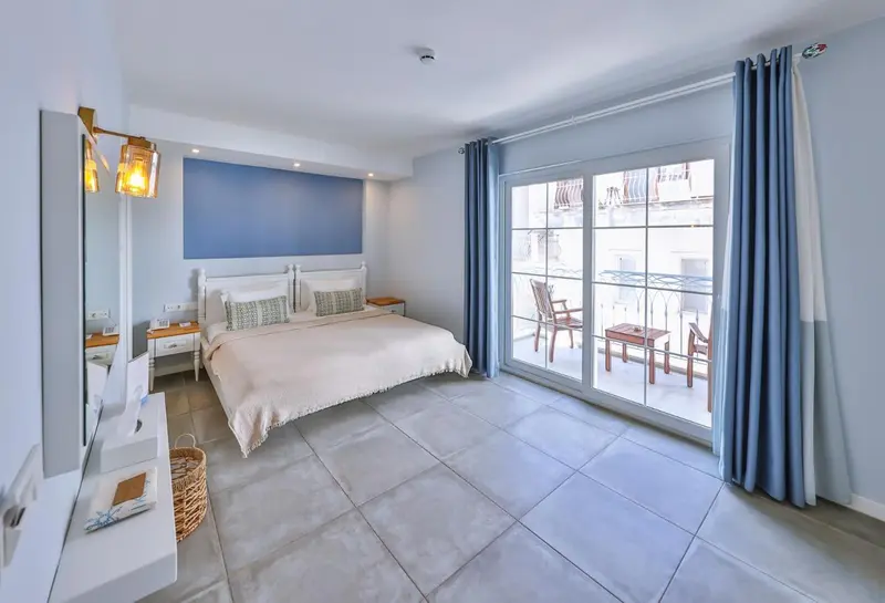 Une chambre lumineuse avec un grand lit et un balcon.
